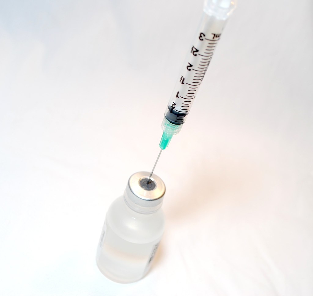 A needle sticking out of a small vaccine bottle